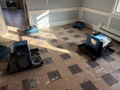 Dehumidifiers and air movers drying a room with the flooring removed