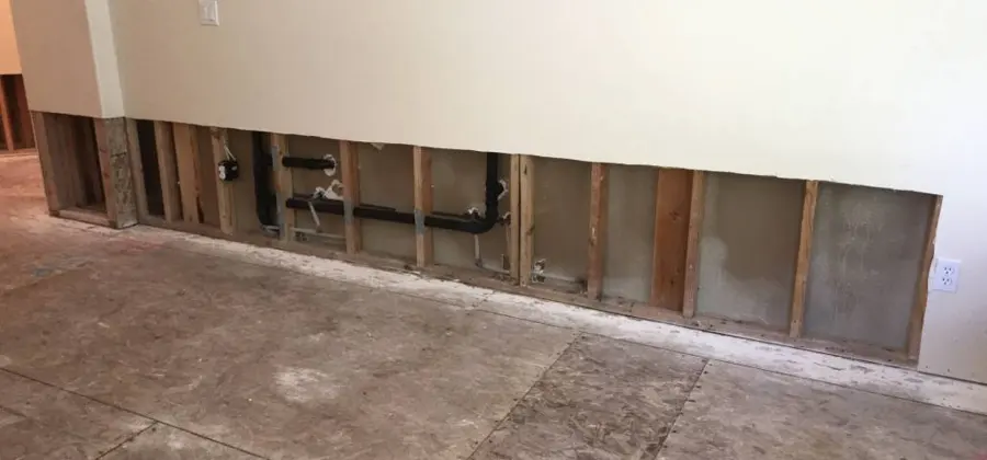 Drywall cut away along the bottom of a wall so the studs can dry