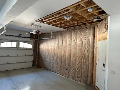 A garage ceiling opened to the joists with the wall insulation exposed for drying