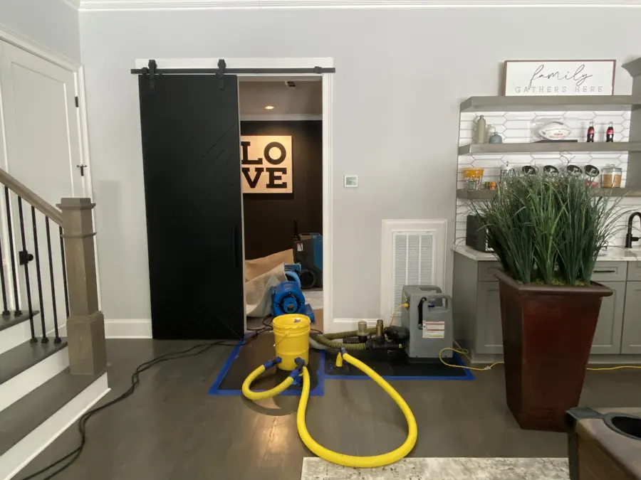 A drying unit with yellow hoses set on the floor of a home during a dry-out