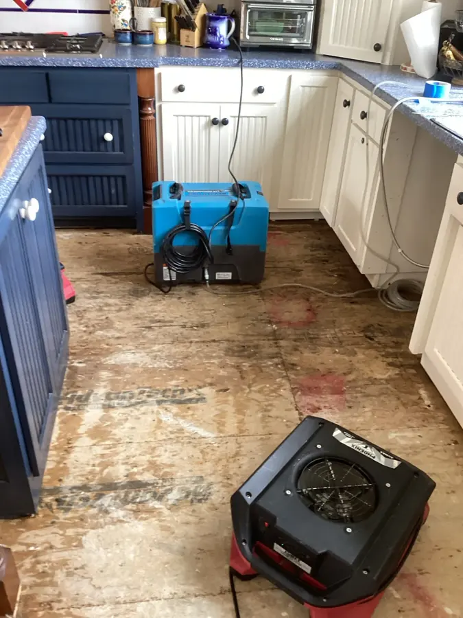 A dehumidifier and an air mover drying a kitchen floor with the flooring pulled up, appliance leak water damage in Concord, NH