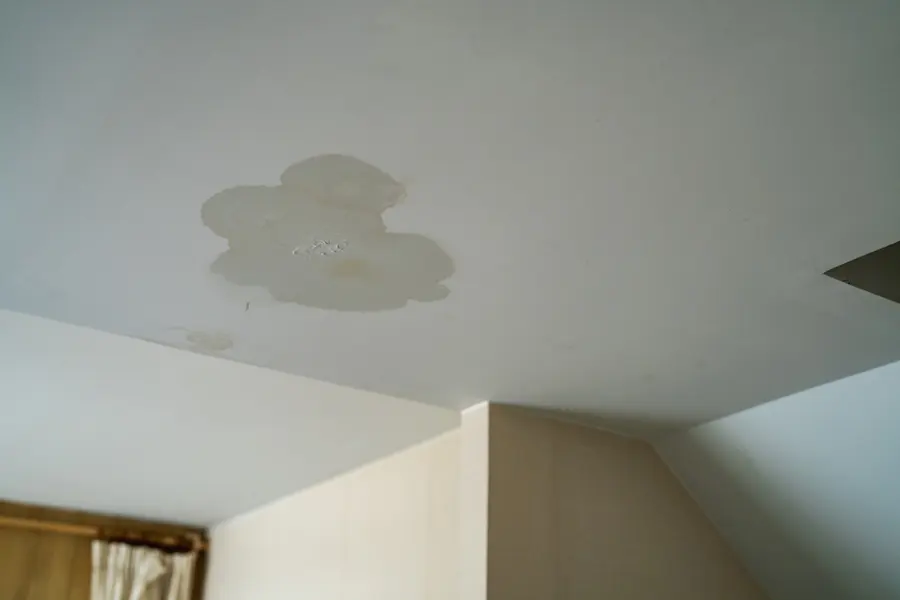 A yellow water stain spreading across a white ceiling, ceiling leak water damage in Concord, NH