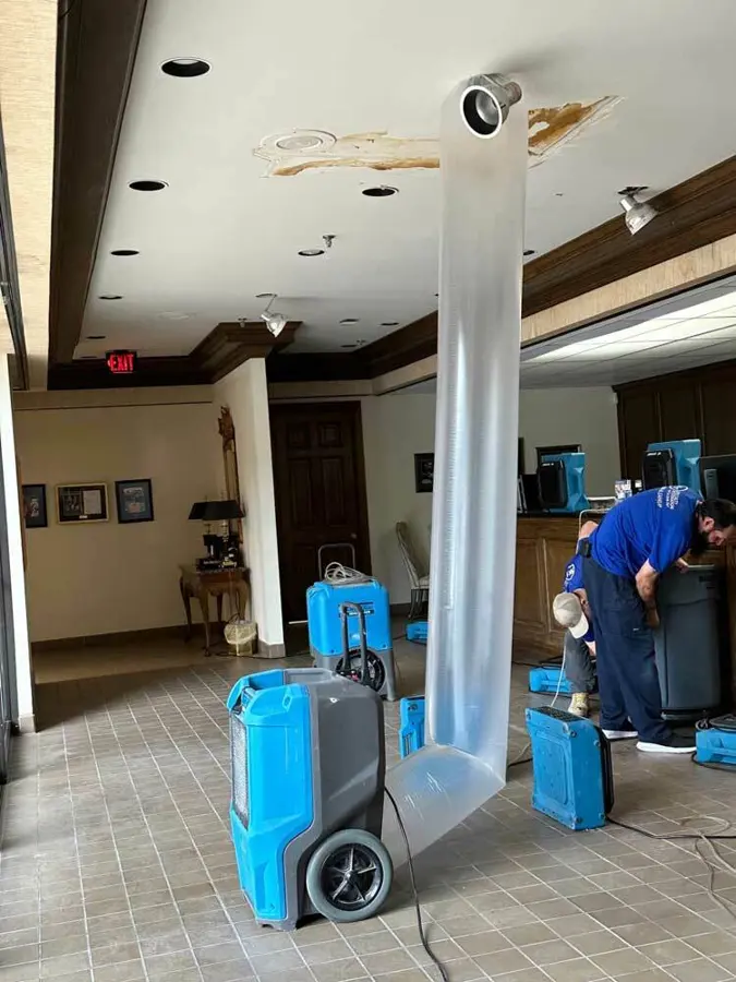 Dehumidifiers and a plastic air duct drying a commercial lobby with a stained ceiling, commercial water damage in Concord, NH
