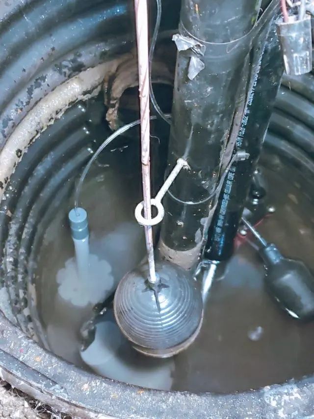 A sump pit filled with water around the pump and float switch, sump pump failure cleanup in Concord, NH