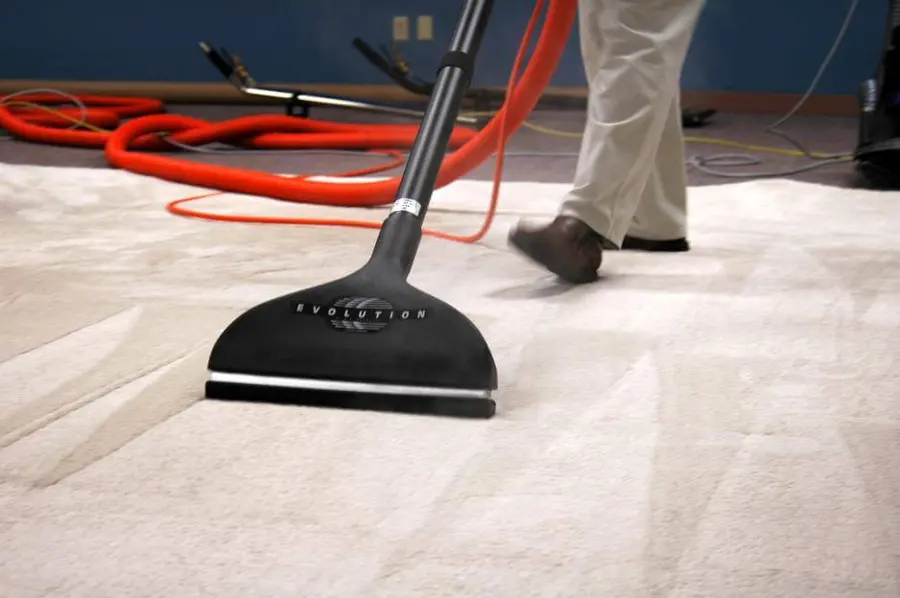 A carpet extraction wand with red hoses pulling water out of wall-to-wall carpet, water extraction in Concord, NH